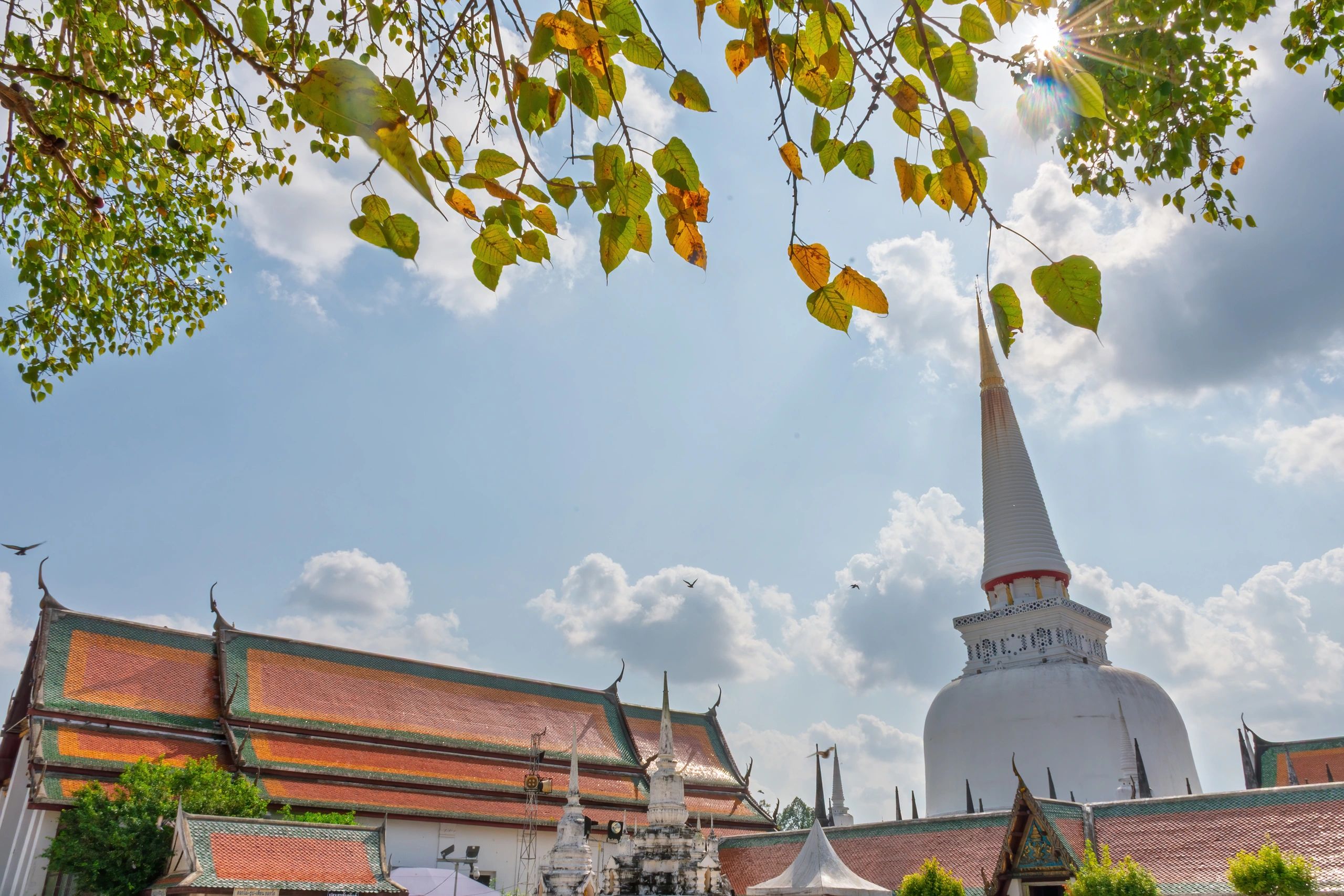 White stupa and temple buildings under a sunny sky in Thailand