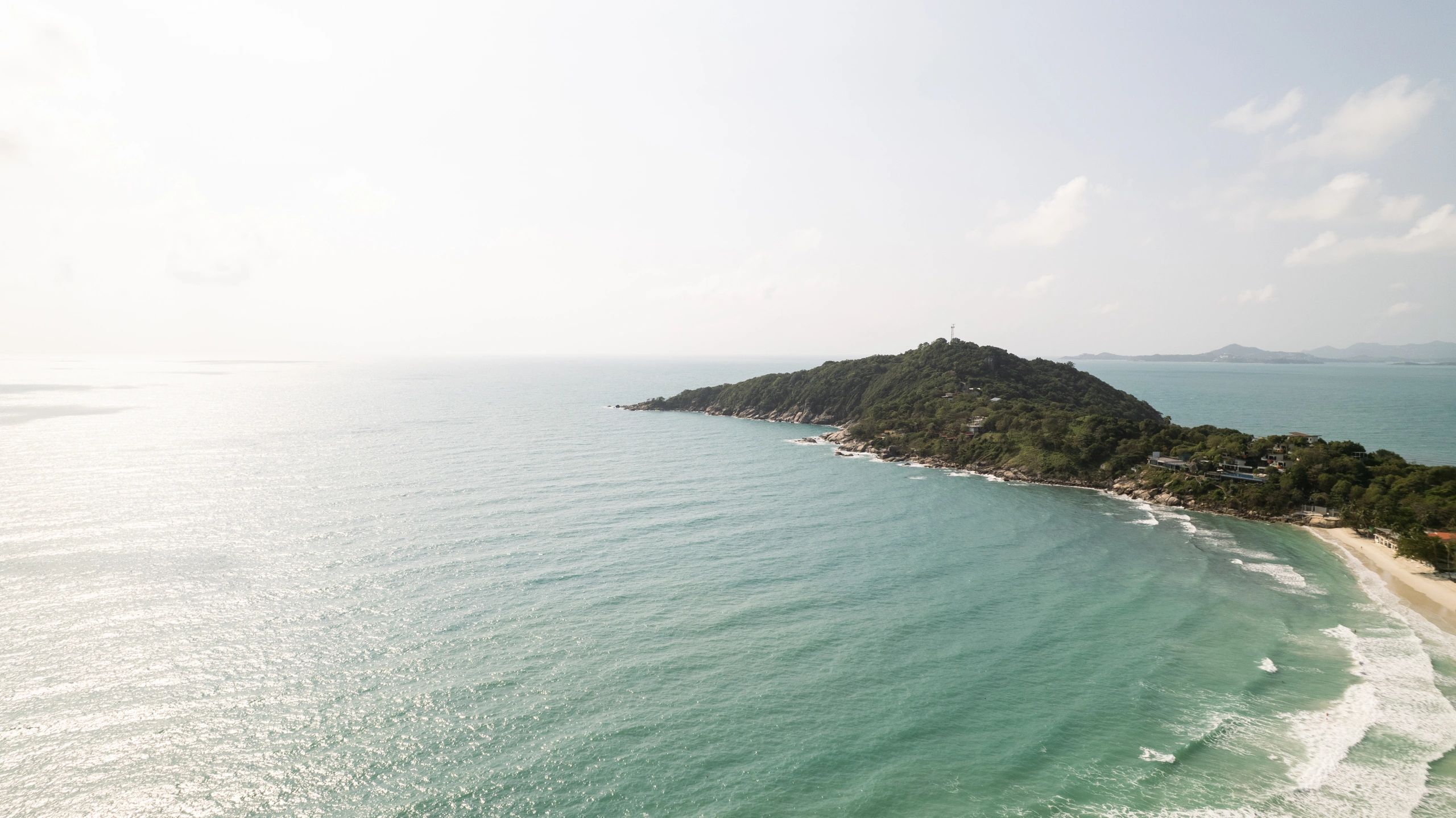 Tropical coastline in Thailand with a lush green island and calm blue water